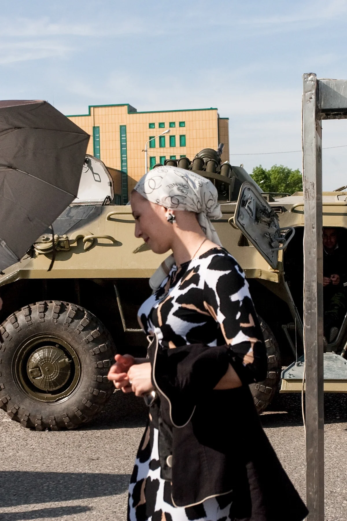 A woman in a headscarf walks past an armoured vehicle in Grozny.