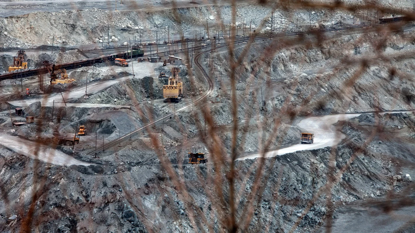 Excavators and trucks on the terraced slopes of an open-pit asbestos mine in Asbest, Russia.